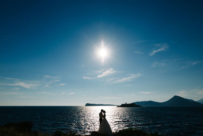 Silhouette man standing in sea against sky