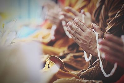 Midsection of monks praying while holding thread