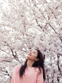 Portrait of young woman with pink cherry blossoms in spring