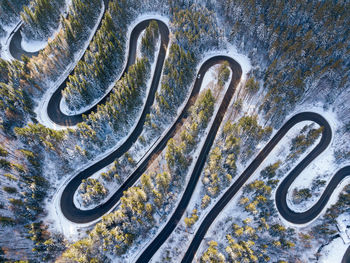 Winding road through the forest, from high mountain pass, in winter time