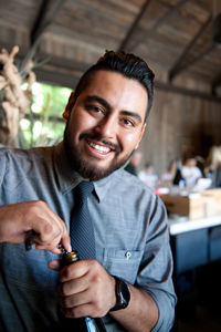 Portrait of young man opening wine bottle