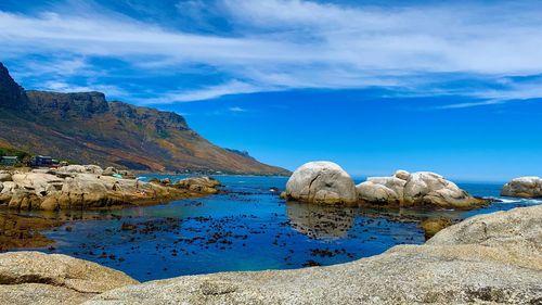 Rocks by sea against blue sky