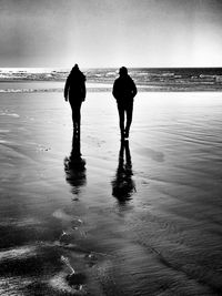 Rear view of silhouette people walking on beach