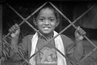 Portrait of smiling boy holding metal fence