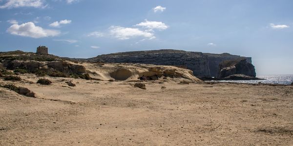 Rock formations on beach against sky