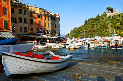 Boats moored at harbor by buildings against clear blue sky