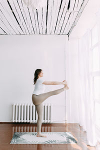 Side view of woman standing against wall