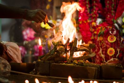 Midsection of man holding burning candles in temple