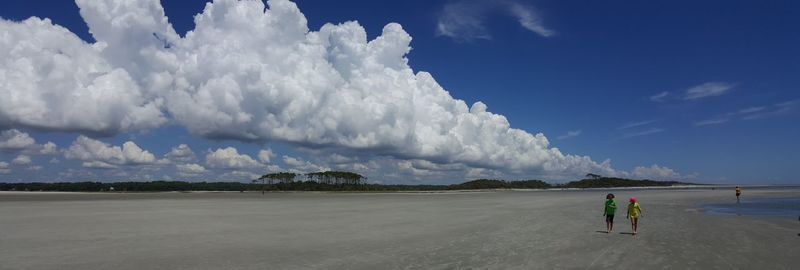 Panoramic view of man walking on beach against sky