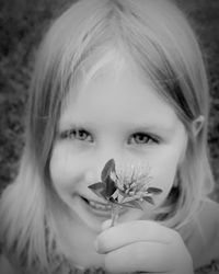 Close-up portrait of smiling girl holding flower