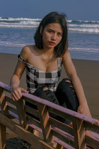 Portrait of young woman sitting on beach at beach during sunny day