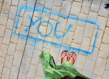 Low section of person standing on footpath by swimming pool