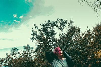 Low angle view of young woman against trees