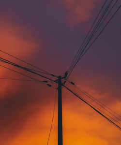 Low angle view of silhouette electricity pylon against dramatic sky