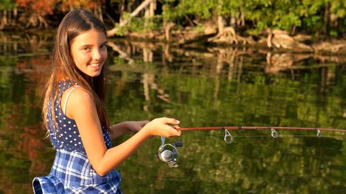 Portrait of happy girl fishing in river