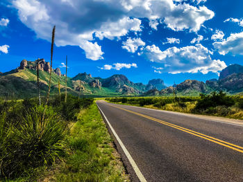 Road leading towards mountains against sky