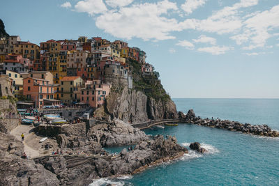 Buildings by sea against sky