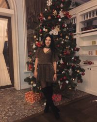 Portrait of woman standing against christmas tree
