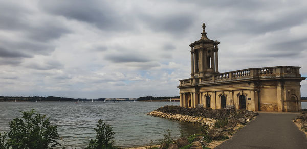 View of historic building against lake and cloudy sky