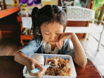 Cute girl eating food while sitting at home