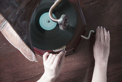 Ghostly hands in black gloves turn the handle of an old gramophone, halloween