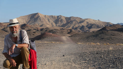 Senior man sitting on mountain in the desert 