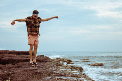 Rear view of woman standing on beach against sky