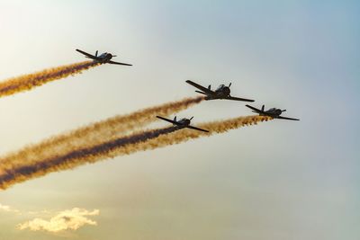 Low angle view of airplanes flying against sky during sunset