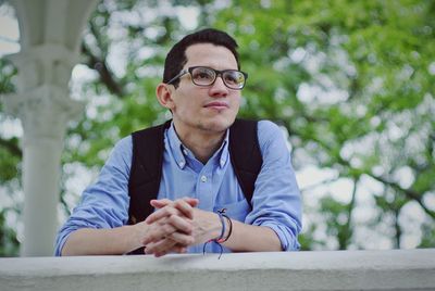 Low angle view of thoughtful man looking away while leaning on retaining wall