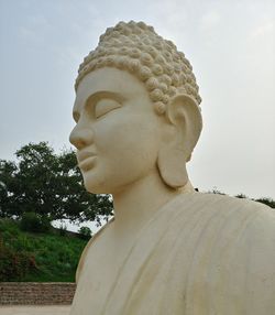 Close-up of buddha statue against sky