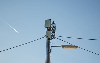 Low angle view of telephone pole against clear blue sky