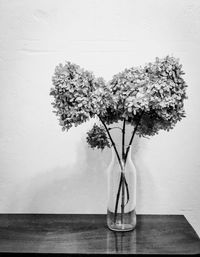 Flower vase on table against wall