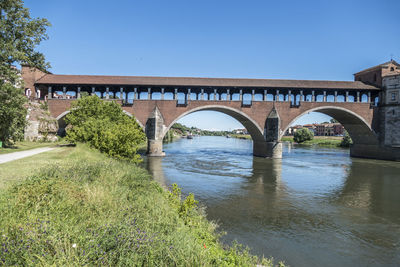 Arch bridge over river against clear sky