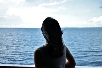 Rear view of young woman standing against sea