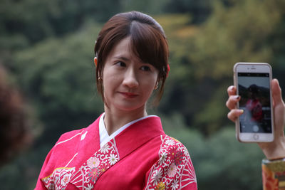 Portrait of smiling young woman using mobile phone outdoors