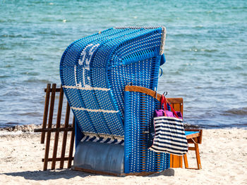 Deck chairs on beach against blue sea