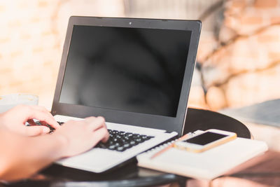 Close-up of businesswoman using laptop on table at sidewalk cafe