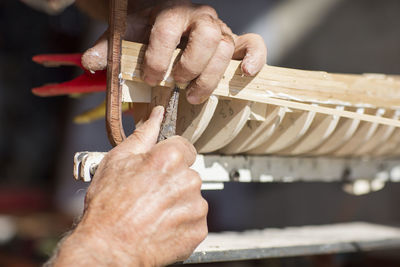 Close-up of man working on wooden boat model