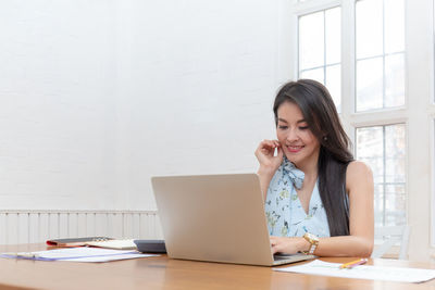 Young woman using phone while sitting on table