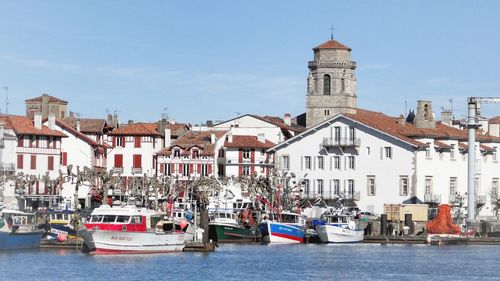 Church and buildings in front of canal against sky on sunny day