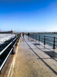 Pier over sea against clear blue sky