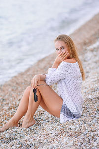 Young woman sitting on sand at beach