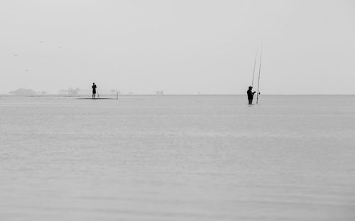 Silhouette people on beach fishing