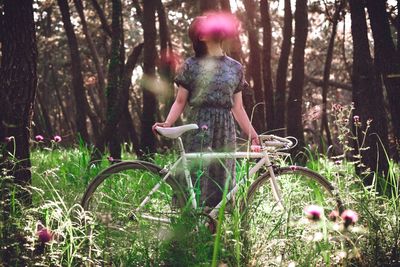 Girl standing by tree in forest