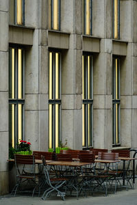 Empty chairs and table against building