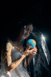 Young woman wearing mask against black background