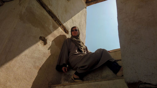 Low angle view of woman looking away sitting on staircase