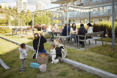 Neighbors relaxing and raking leaves in communal outdoor area