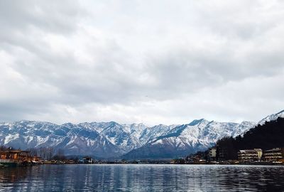 Scenic view of lake by snowcapped mountains against sky