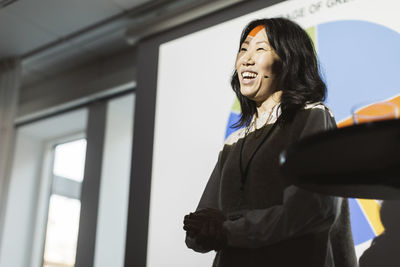 Smiling female entrepreneur giving presentation during seminar at convention center